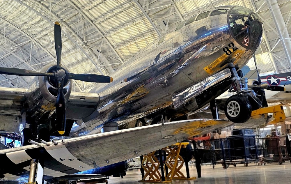 Close-up of a polished, metallic vintage aircraft in a hangar with visible propeller and landing gear.