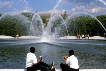 a fountain with people in front of a body of water