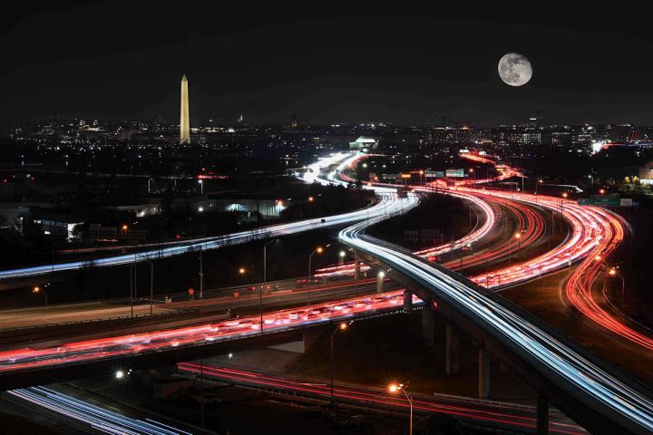 Night view of VA I-395 with light trails and a full moon in the sky.