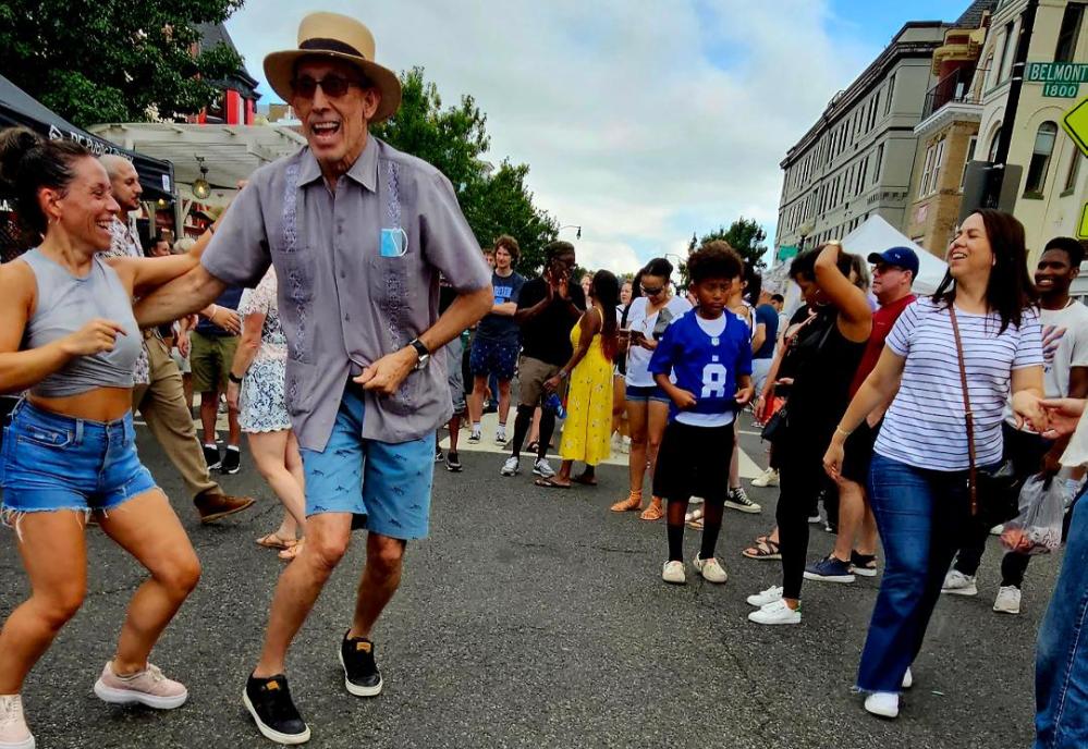 People dancing joyfully on a city street during a festival.