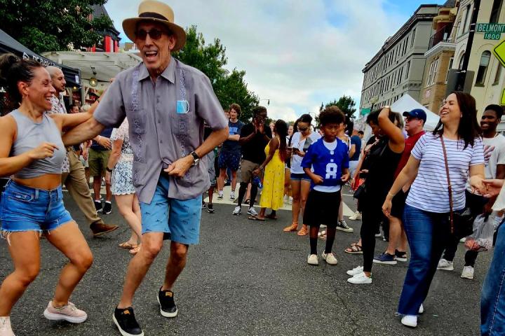 People dancing joyfully on a city street during a festival.
