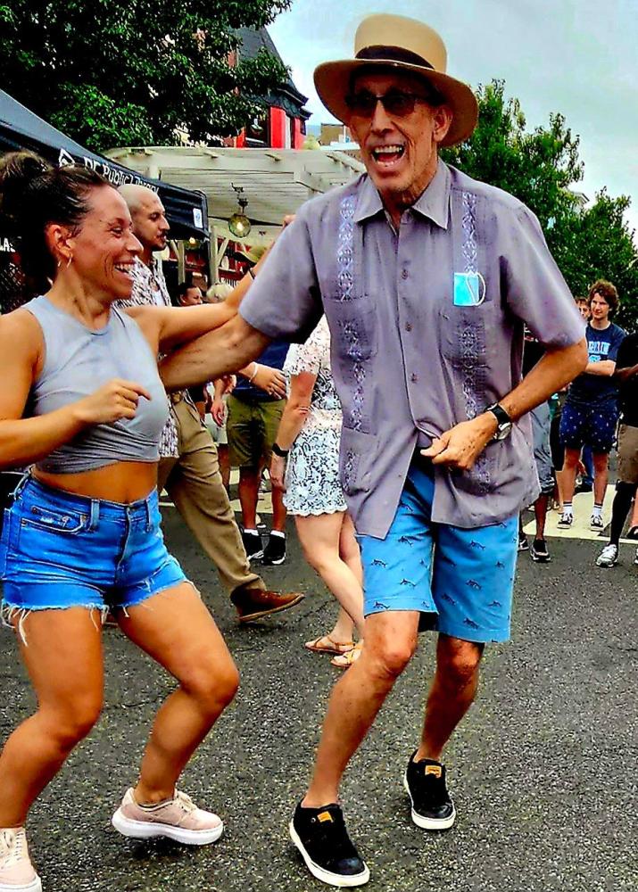 A man and woman dancing joyfully outdoors at an event.