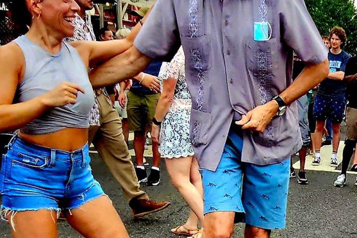 A man and woman dancing joyfully outdoors at an event.