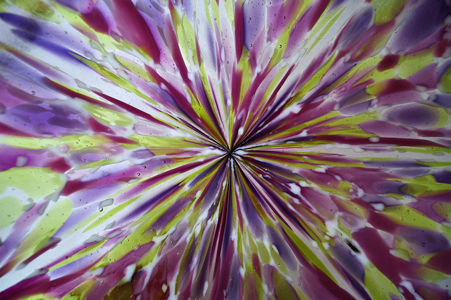 Abstract pattern with radial streaks in purple, yellow, and white colors in a glass bowl.